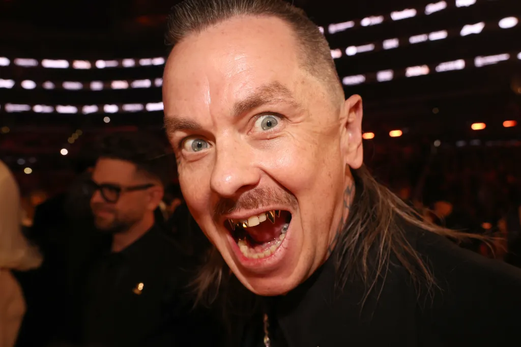 Sid Wilson with a wide-eyed expression and gold grill teeth.