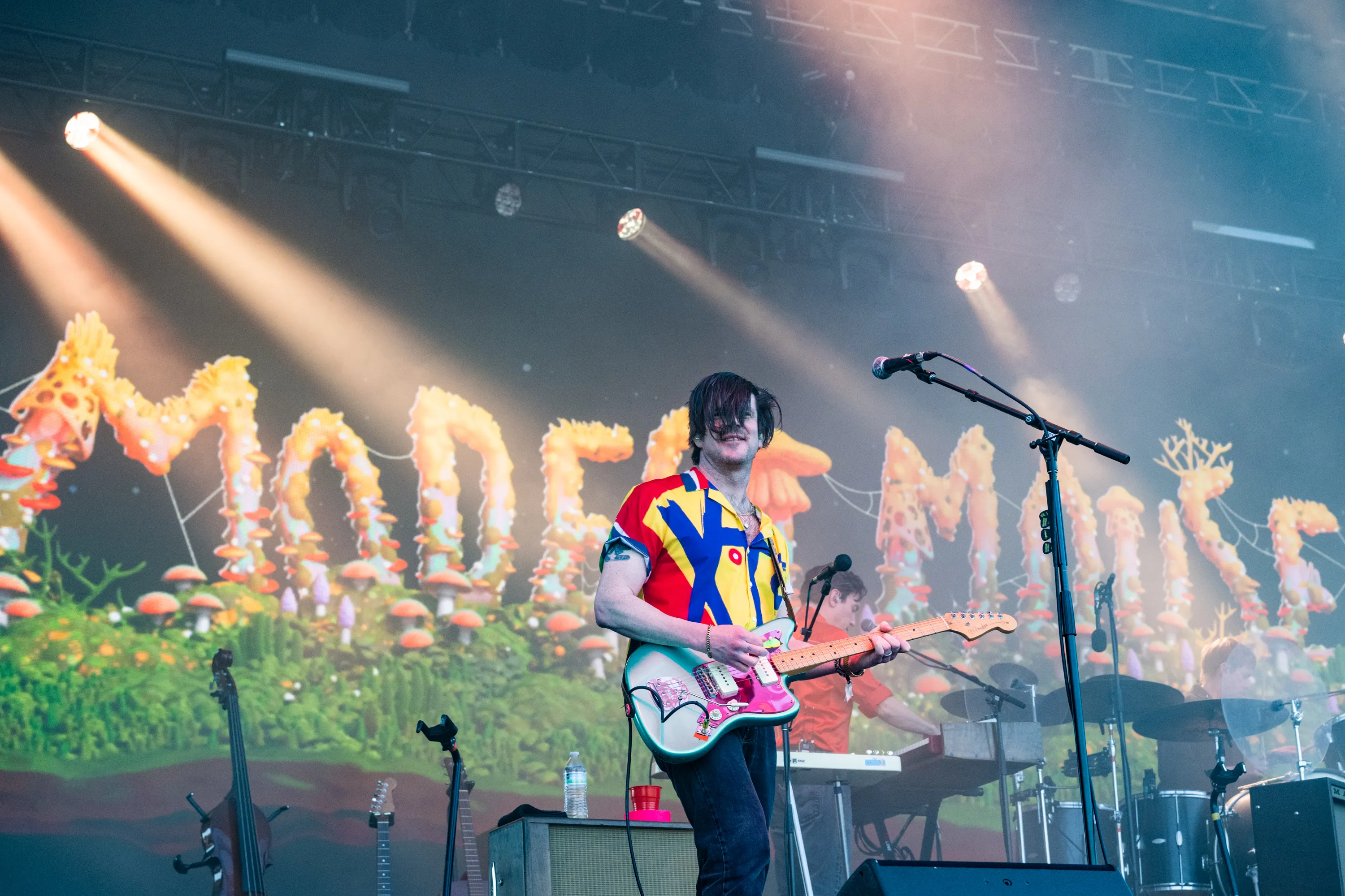 Simon O'Connor of Modest Mouse performs on stage with a colorful backdrop.