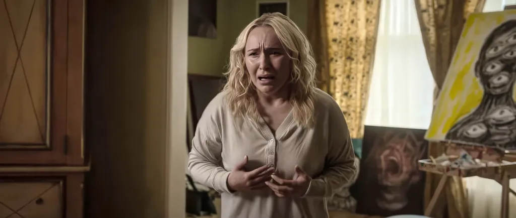 Hayden Panettiere in a light long-sleeved shirt, crying in a room with a painting on an easel.