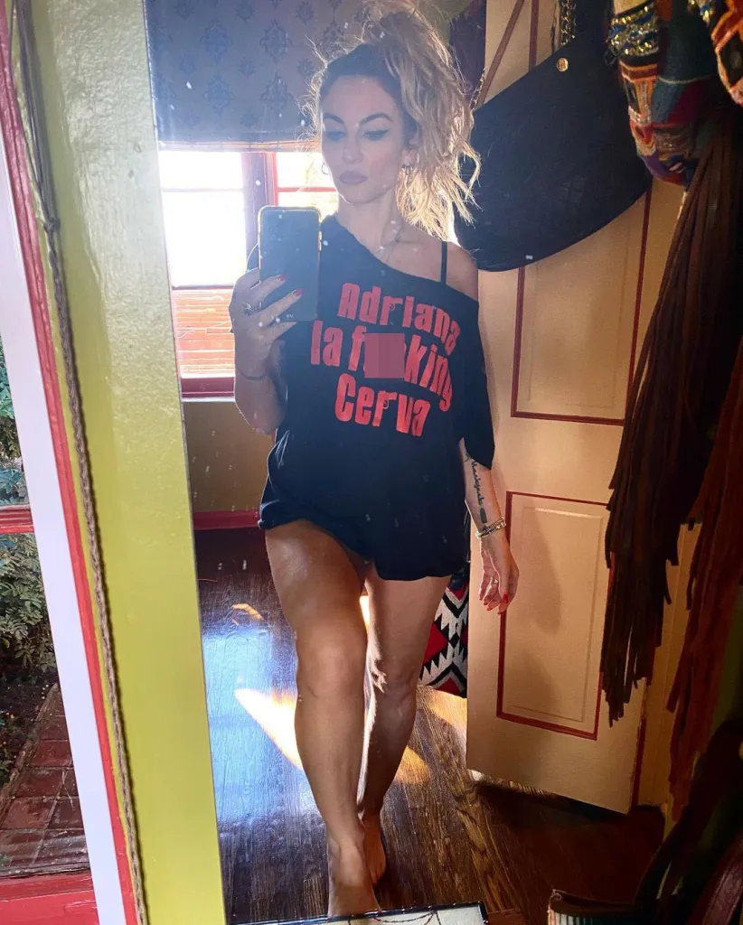 Drea de Matteo taking a mirror selfie in a black t-shirt that reads