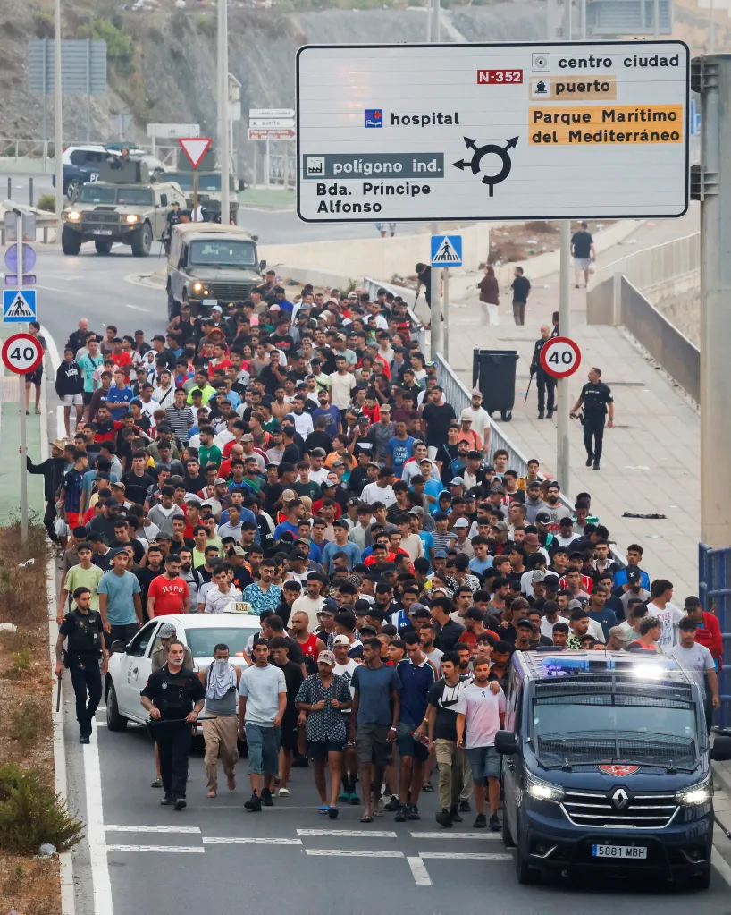 Spanish officers escort a large group of migrants who had illegally crossed into Spanish territory on Aug. 1, 2026.