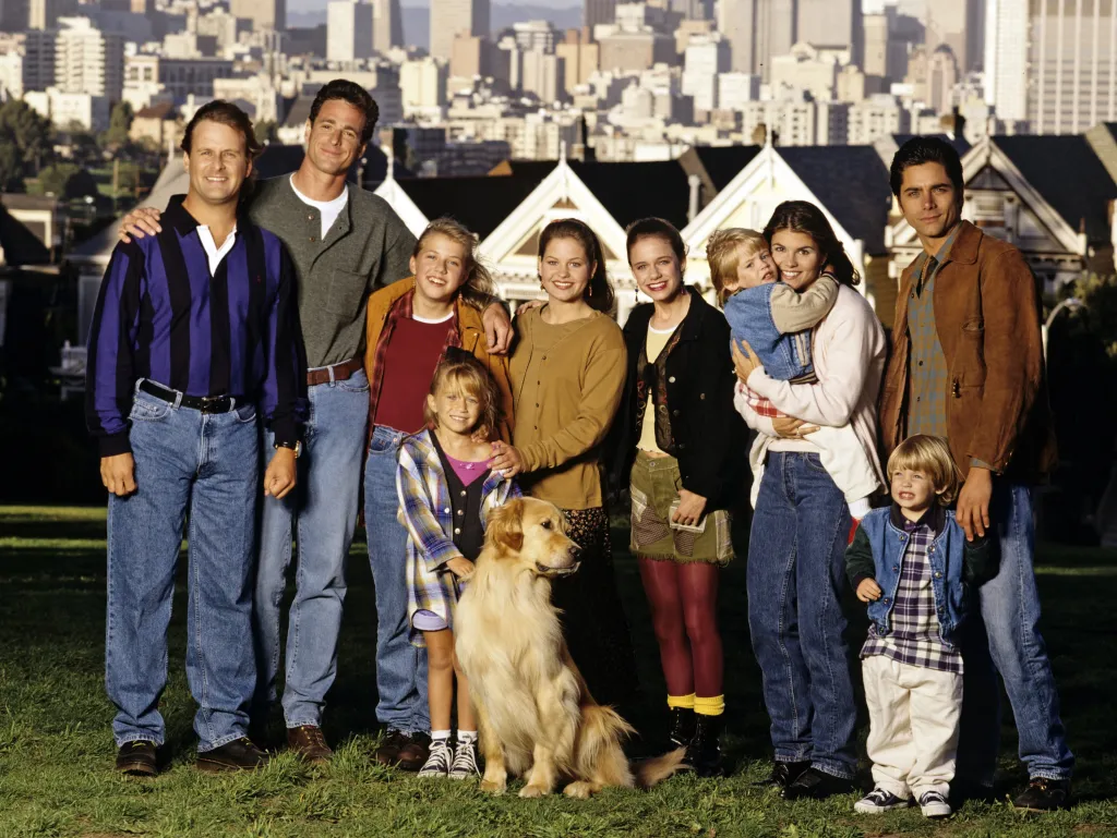 The cast of Full House standing in front of the Painted Ladies and the San Francisco skyline.