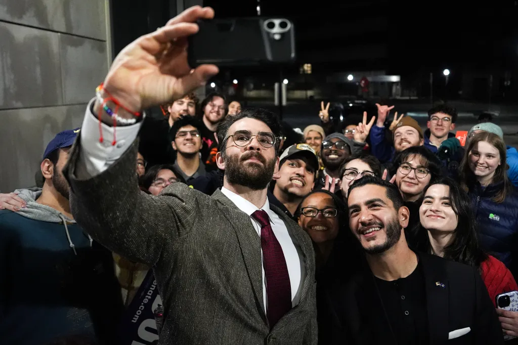 Streamer Hasan Piker, left, and Abdul El-Sayed, a progressive candidate in the Democratic primary for U.S. Senate in Michigan, center right, take a selfie with young fans following a campaign event, Tuesday, April 7, 2026, at the University of Michigan in Ann Arbor, Mich.