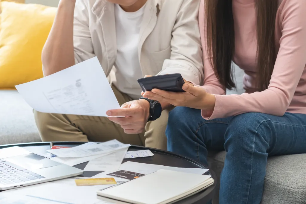 A stressed young Asian couple sits together while calculating expenses from a credit card bill on Saturday, April 15, 2023. (1857730707)