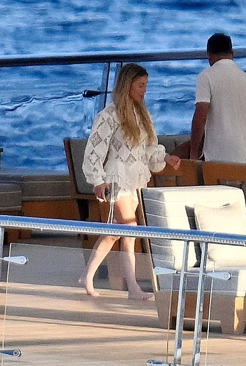 Sydney Sweeney in a white embroidered summer dress on the deck of the yacht Rising Sun in Mallorca.