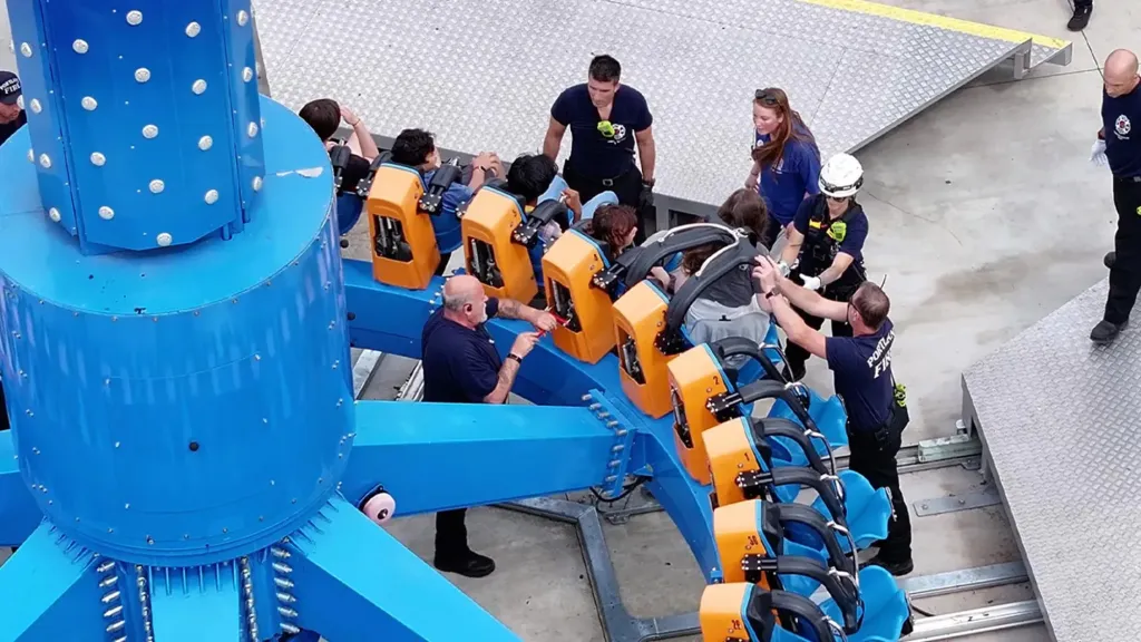 Amusement park ride with passengers stuck upside down as emergency workers attend to them.