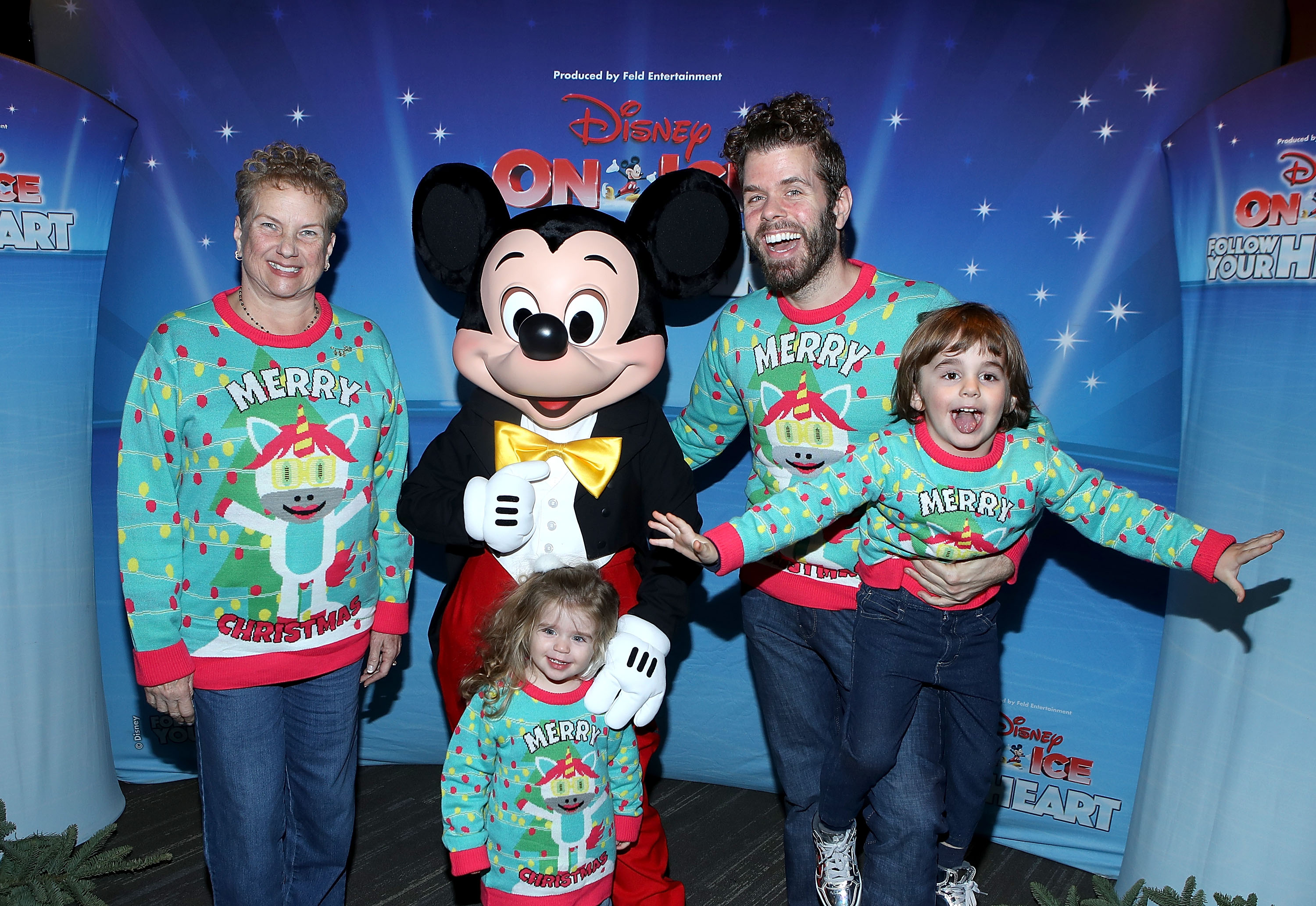 Perez Hilton, his two young children, and Teresita Lavandeira pose with Mickey Mouse in front of a Disney On Ice backdrop.