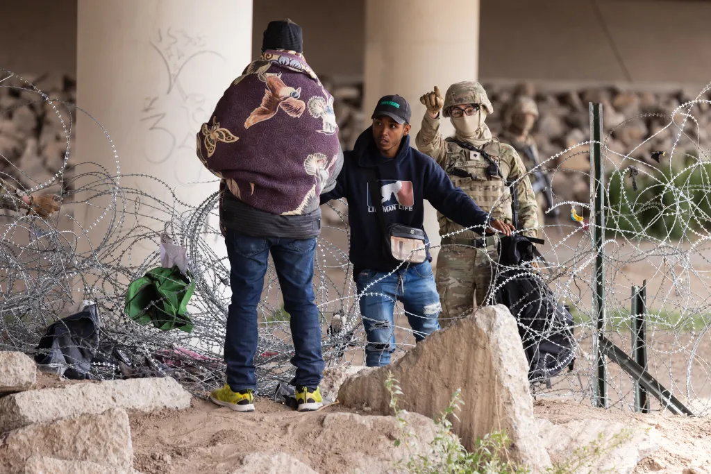 Texas National Guard soldiers push back a large group of migrants who crossed the border illegally and breached concertina wire barriers along the Rio Grande river in El Paso, Texas, on Tuesday, March 26, 2024.