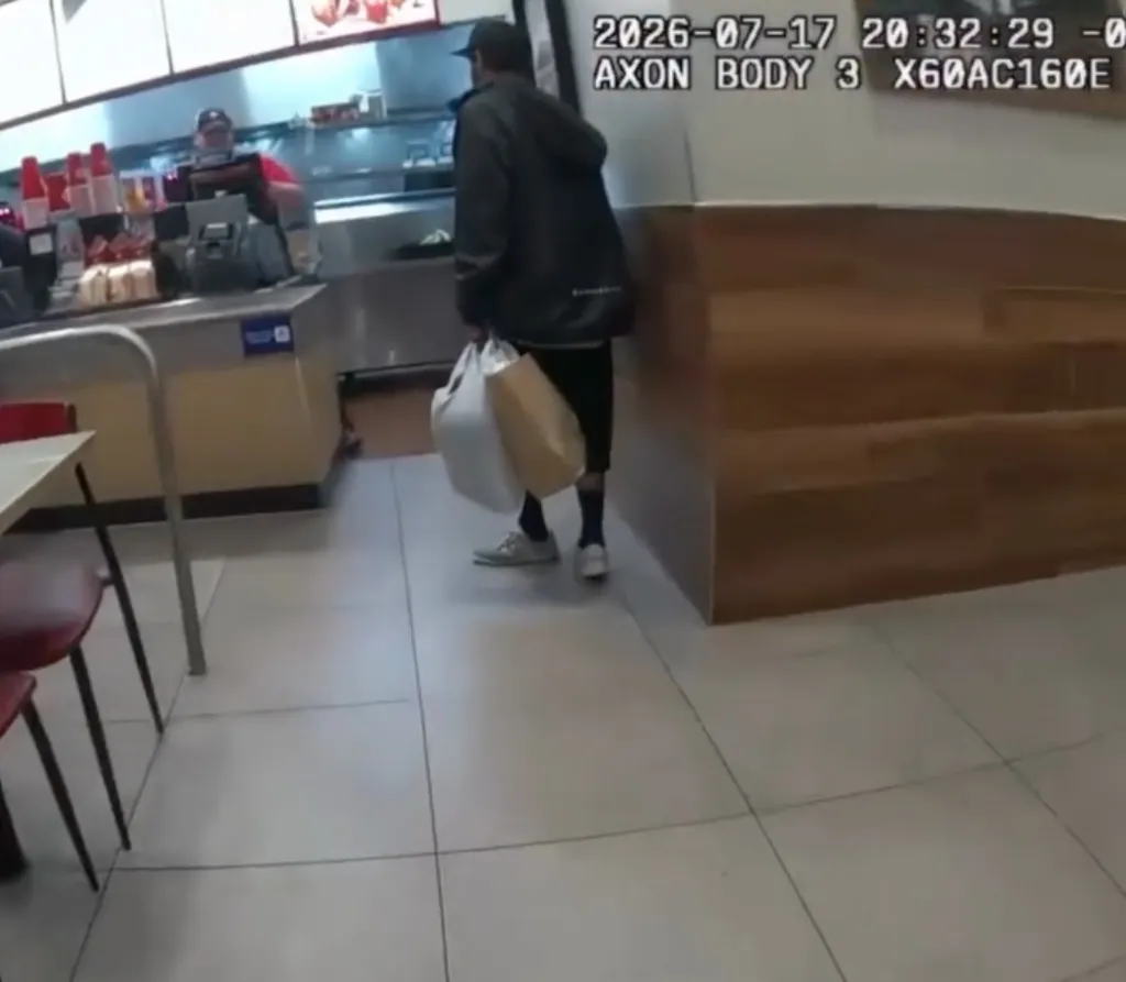 Man with shopping bags walks into a fast-food restaurant where police officers are eating.