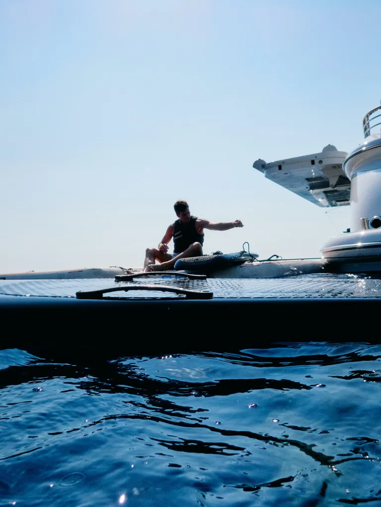 Tom Brady sitting on a boat, casting a fishing line.