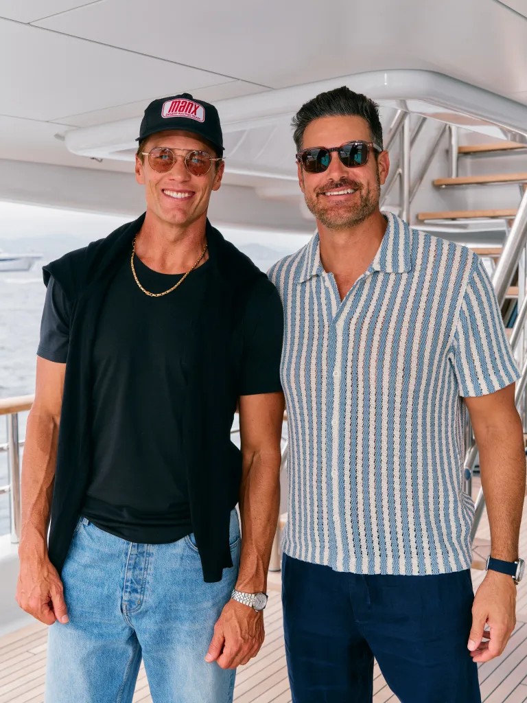 Tom Brady with another man, smiling on a yacht.
