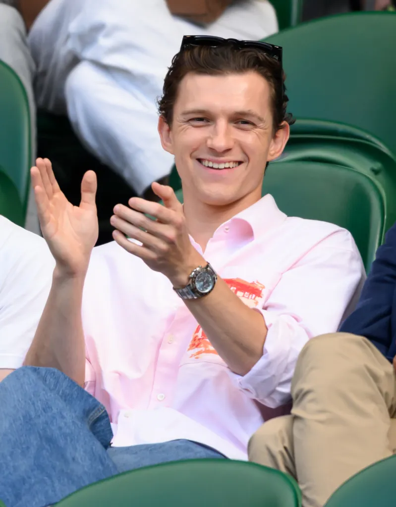Tom Holland claps and smiles courtside at Wimbledon.