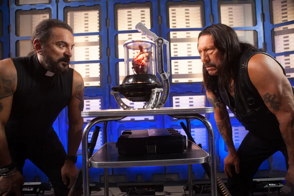 Tom Savini and Danny Trejo looking at a human heart in a scientific container.