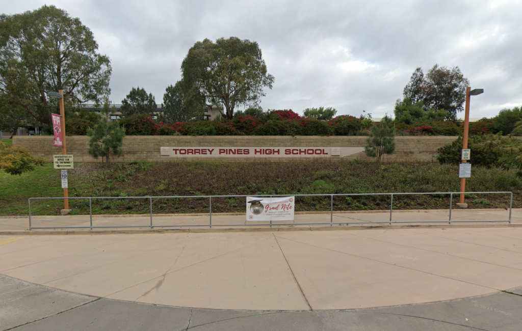 Torrey Pines High School entrance with its name in red letters on a stone wall.