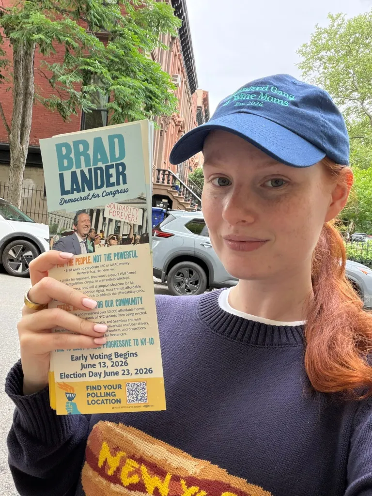 Grace Ryan holds a political flyer for Brad Lander, Democrat for Congress.