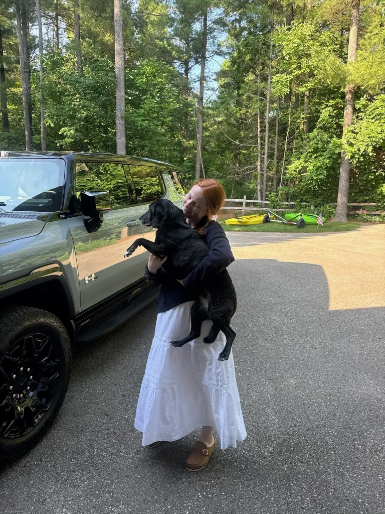 Grace Ryan holding a black dog beside a Hummer.