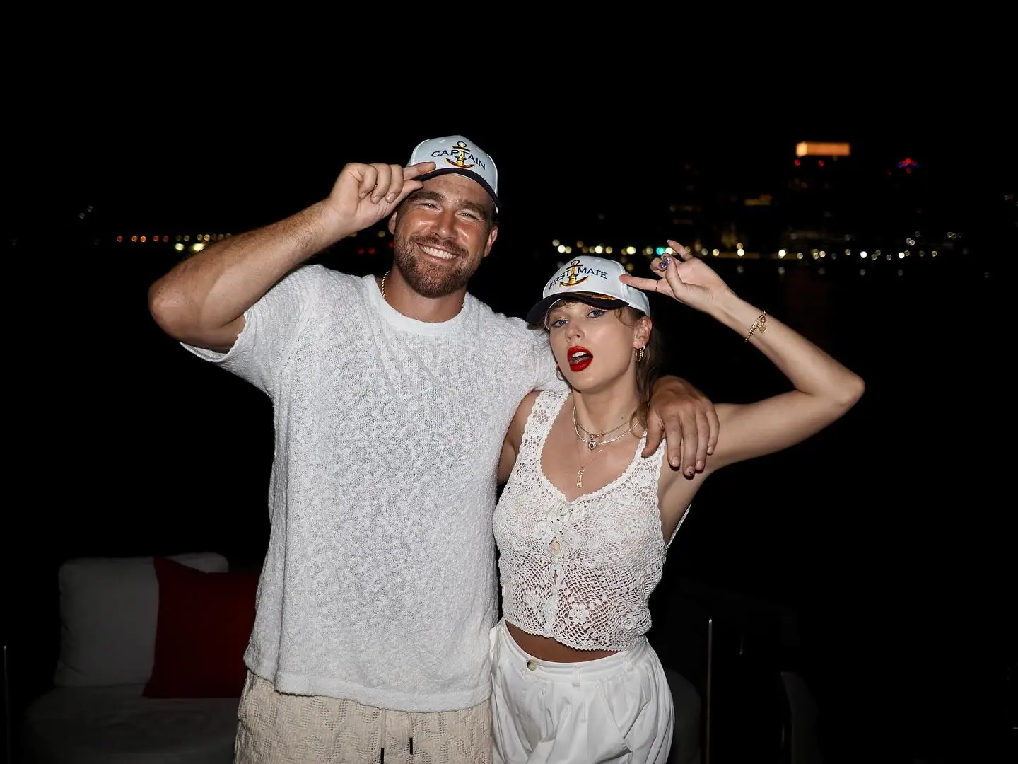 Travis Kelce and Taylor Swift wearing captain and first mate hats.