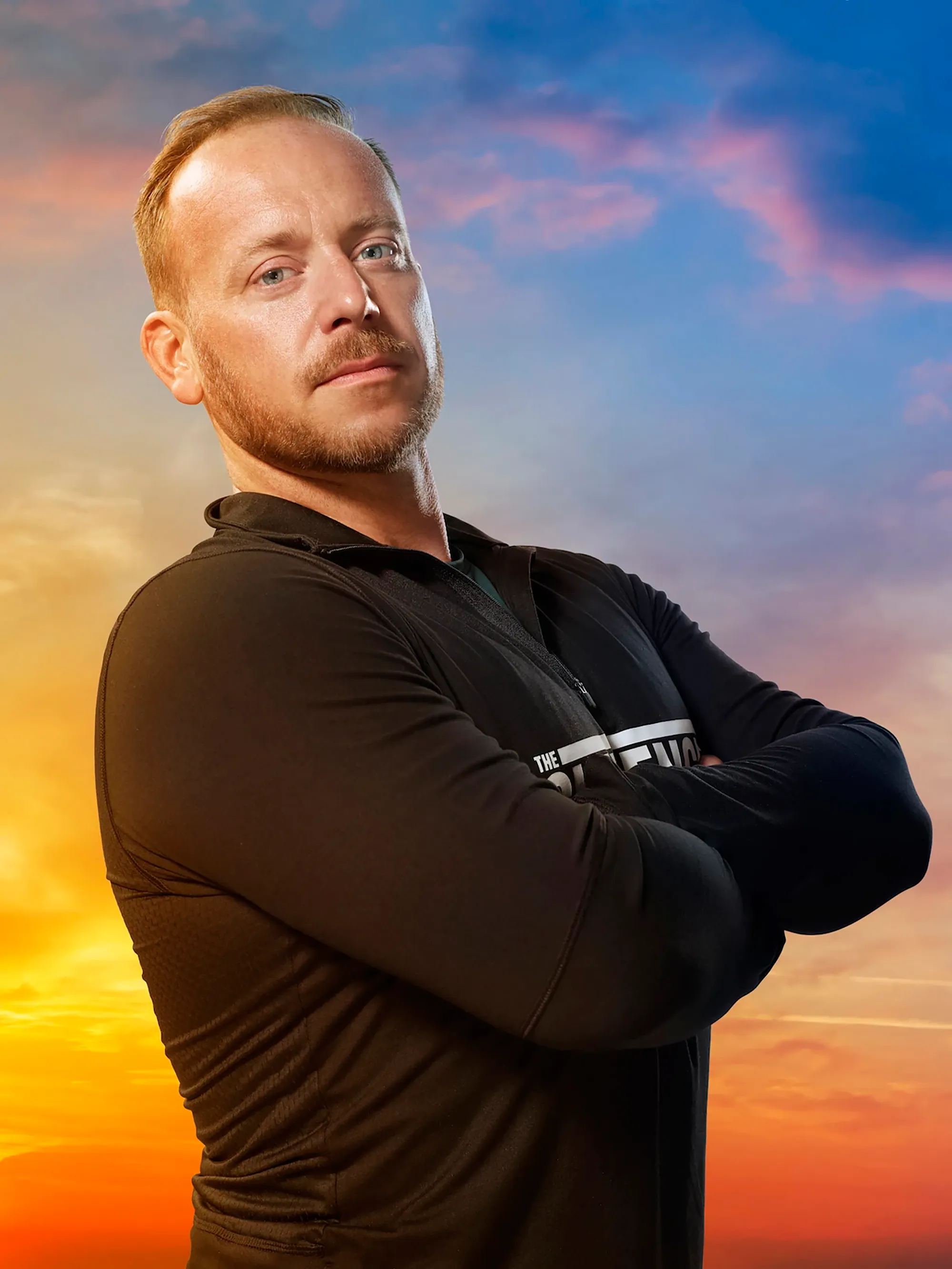 Tyler Duckworth on the Challenge, wearing a black long-sleeved shirt, with a sunset sky in the background.