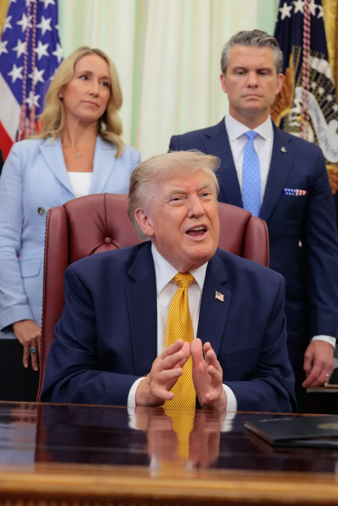 President Trump speaks after signing an executive order, flanked by Jennifer Rauchet and Pete Hegseth.