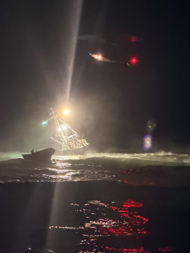 A grounded vessel in Point Reyes National Seashore at night with a bright spotlight on it from a helicopter.
