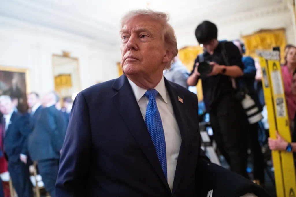 President Donald Trump in a dark suit and blue tie in the East Room of the White House.