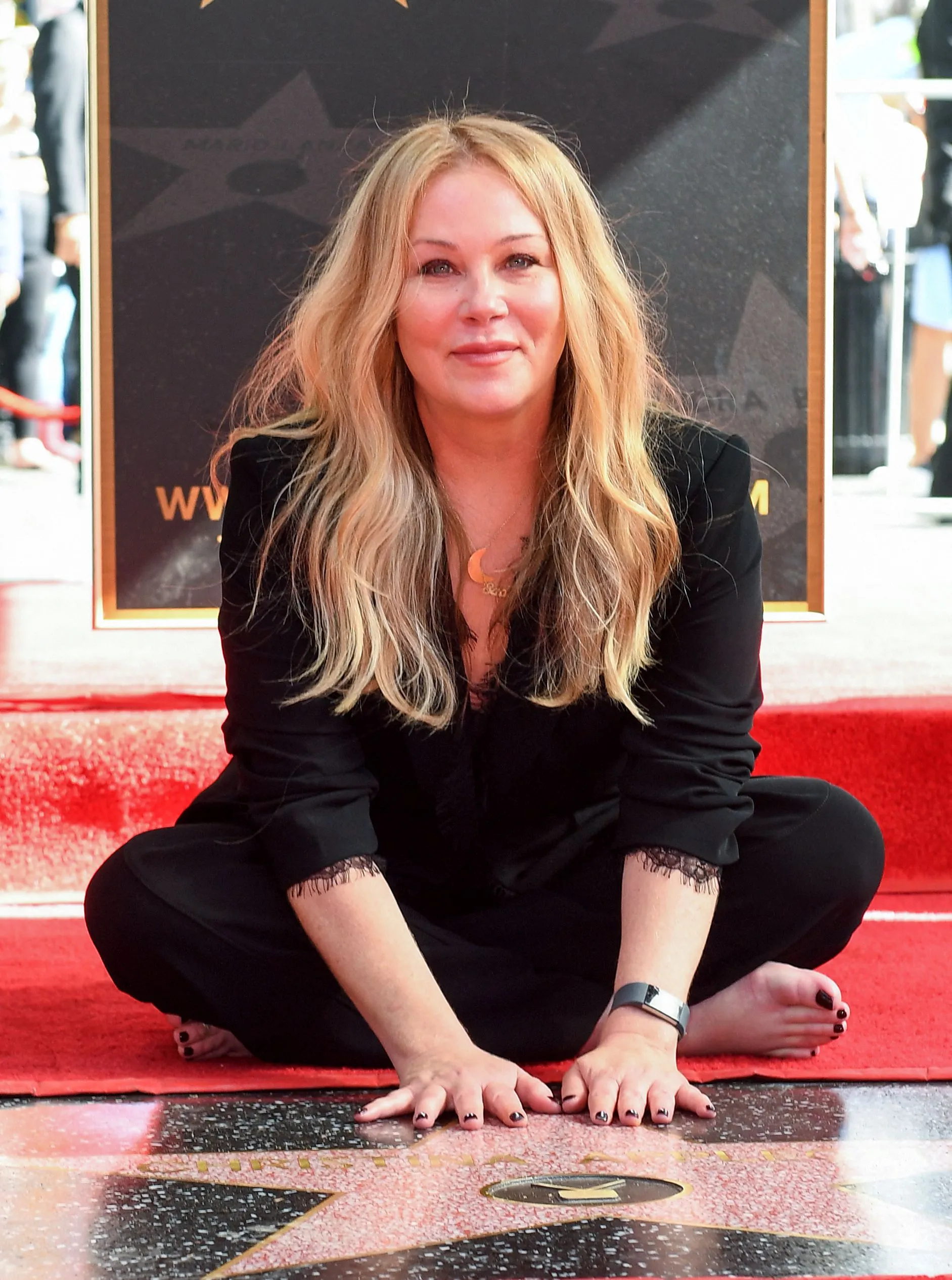 Christina Applegate sits barefoot, cross-legged, next to her newly unveiled star on the Hollywood Walk of Fame.