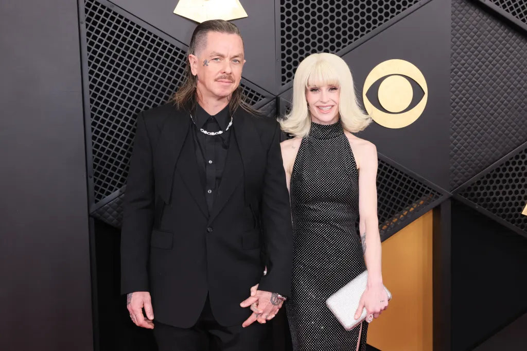 DJ Sid Wilson and TV personality Kelly Osbourne holding hands at the Grammys.