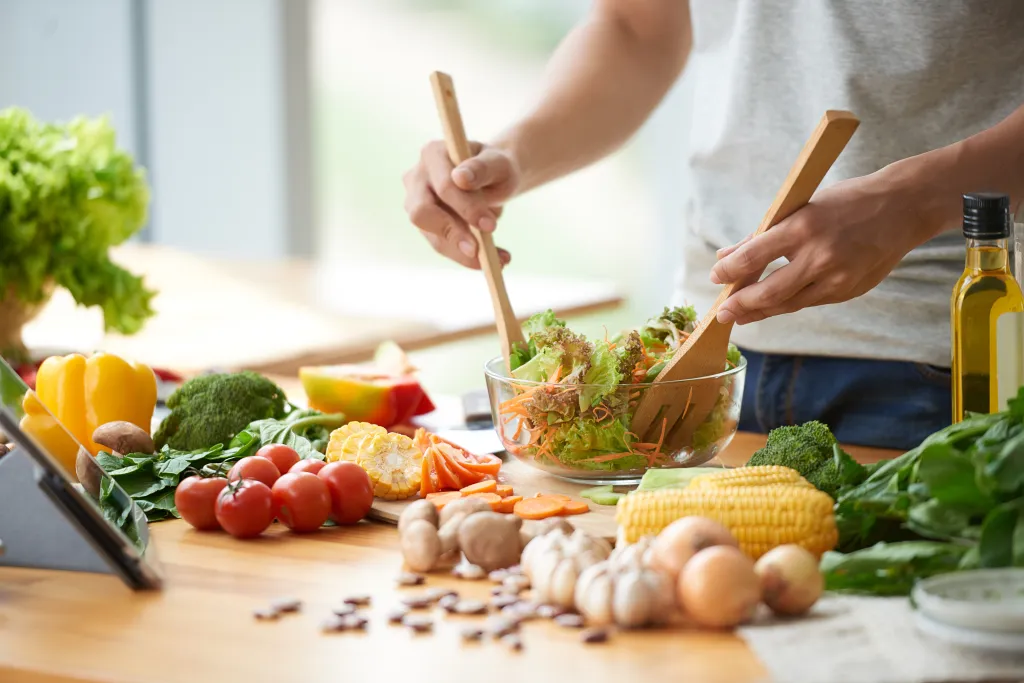 A man mixes a vegetable salad in a bowl.