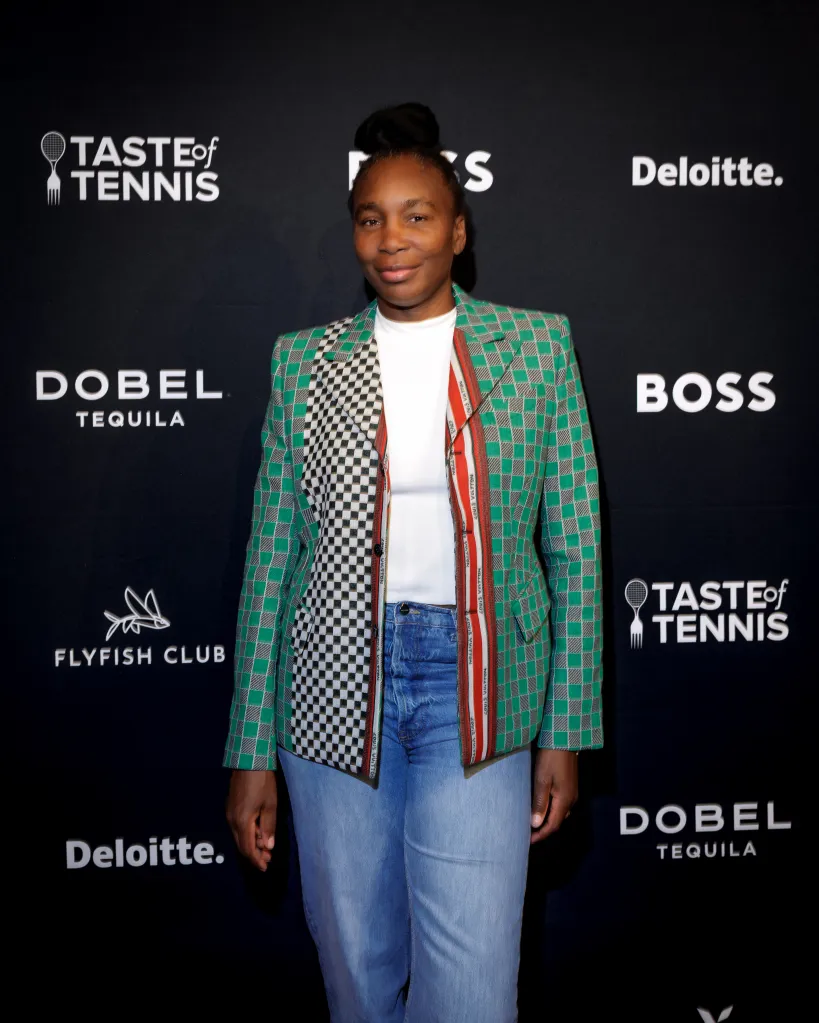 Venus Williams standing in front of a black wall with event and sponsor logos.