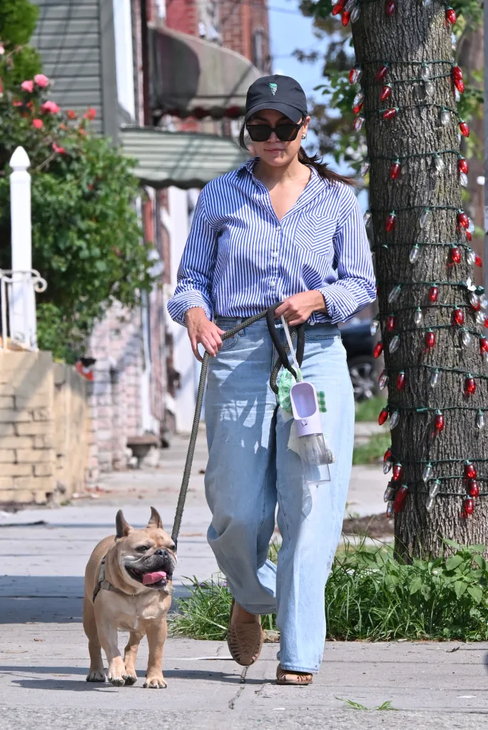 Alexandria Ocasio-Cortez walks her French bulldog, Deco, on a sunny day.