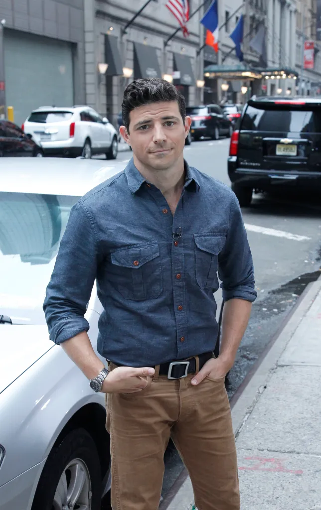 Walt Disney Television News' Matt Gutman wearing a blue button-up shirt and brown pants, standing in a city street.