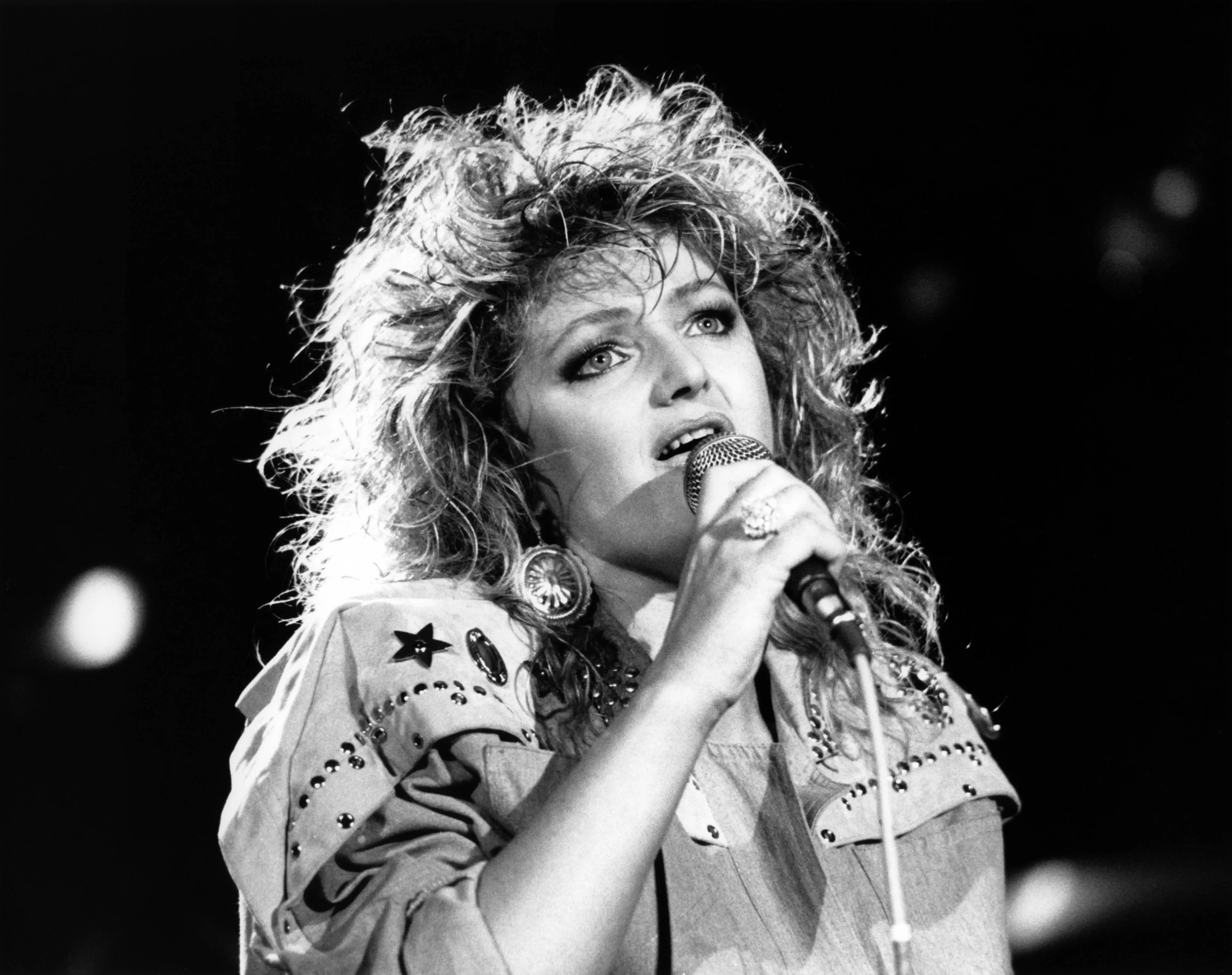 Bonnie Tyler singing into a microphone on stage, circa 1980.