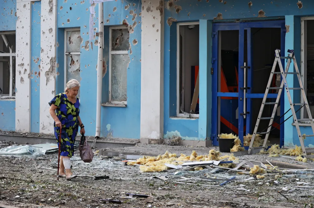 A woman walks past a bank building with a damaged exterior and shattered windows following a Ukrainian drone attack in Belgorod, Russia.