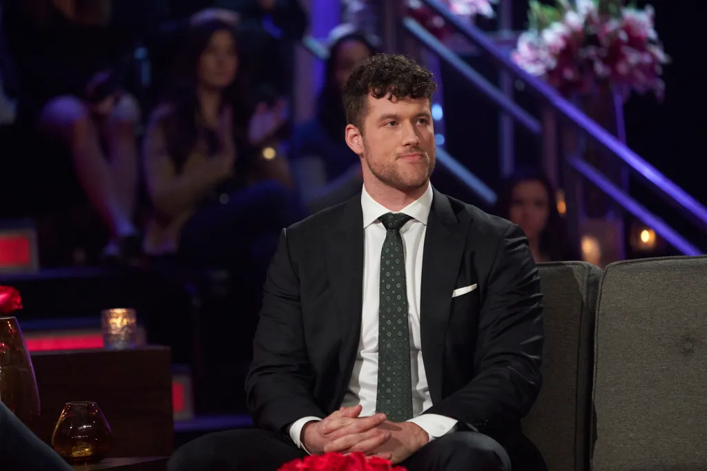 Clayton Echard sitting on a couch wearing a suit.
