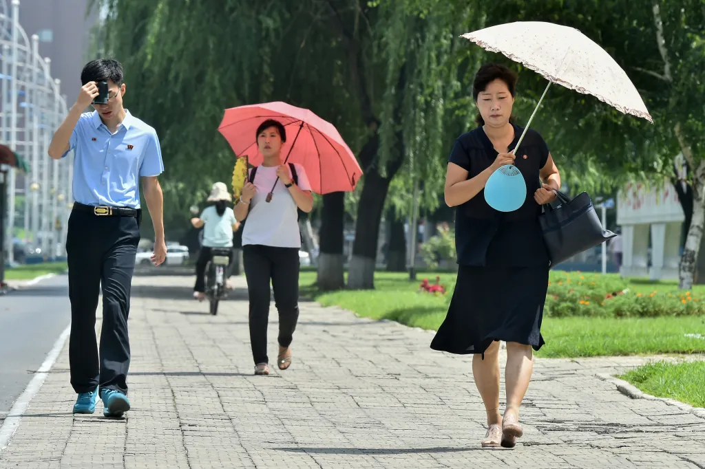 People use umbrellas to shelter from the sun while walking along Mirae Scientists Street in Pyongyang.