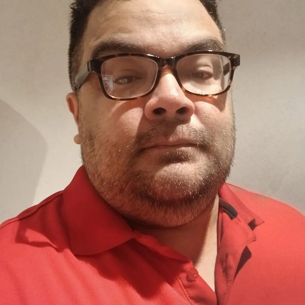 Larry Montes wearing glasses and a red polo shirt.