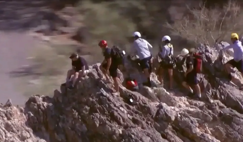 A group of hikers on a rocky mountainside preparing for a helicopter rescue.