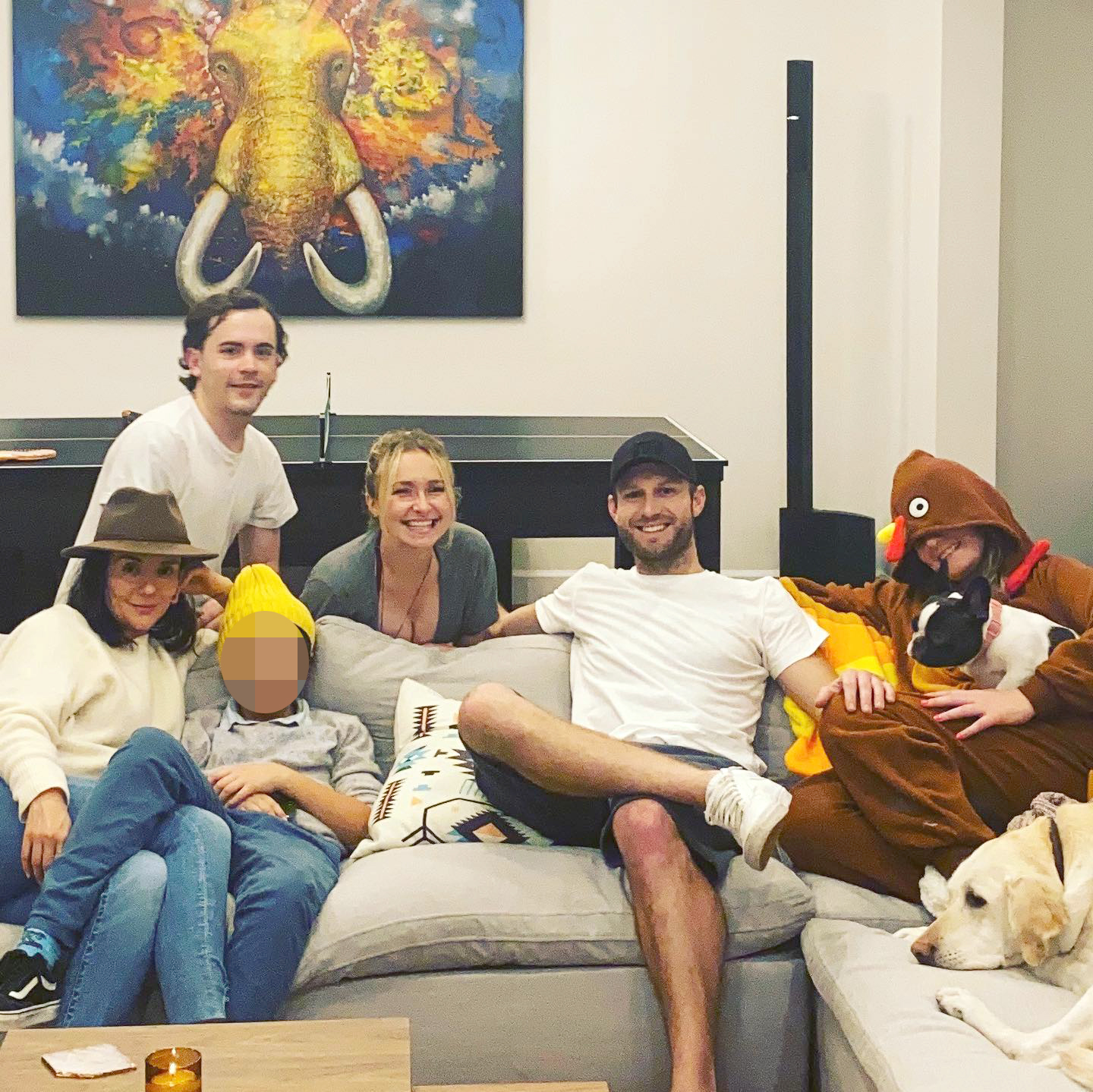 Hayden Panettiere and Brian Hickerson with friends and family on a couch, with one person in a turkey costume holding a small dog.