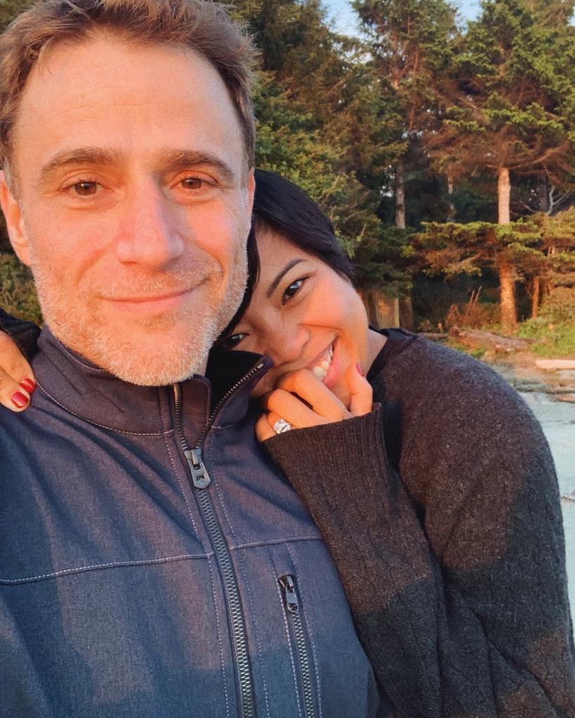 Jen Rubio and her husband Stewart Butterfield smiling with a forest in the background.