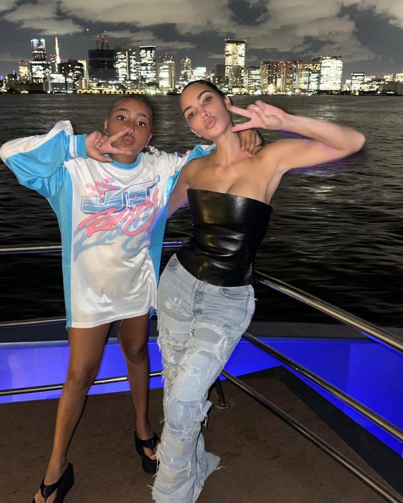 Kim Kardashian and North West posing on a boat at night with a city skyline in the background.
