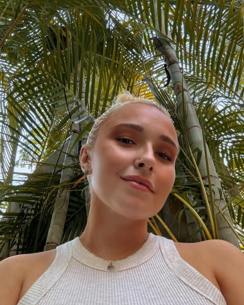 Hayden Panettiere smiling in a close-up shot with palm trees in the background.