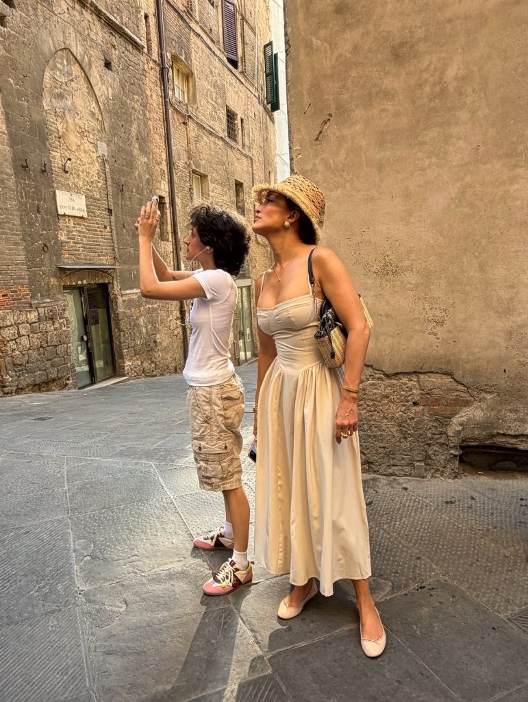 Jennifer Lopez and child looking up at buildings on a road trip through Italy.