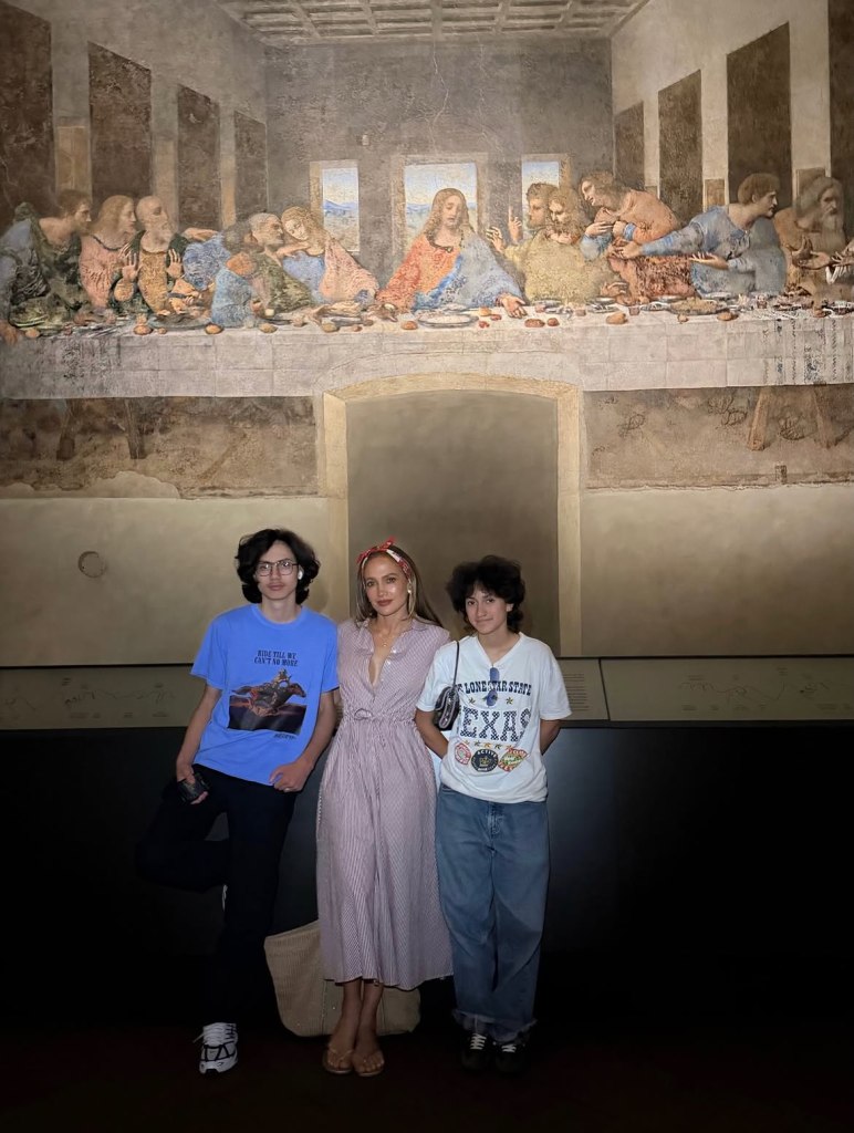 Jennifer Lopez and her twins pose in front of a reproduction of The Last Supper.