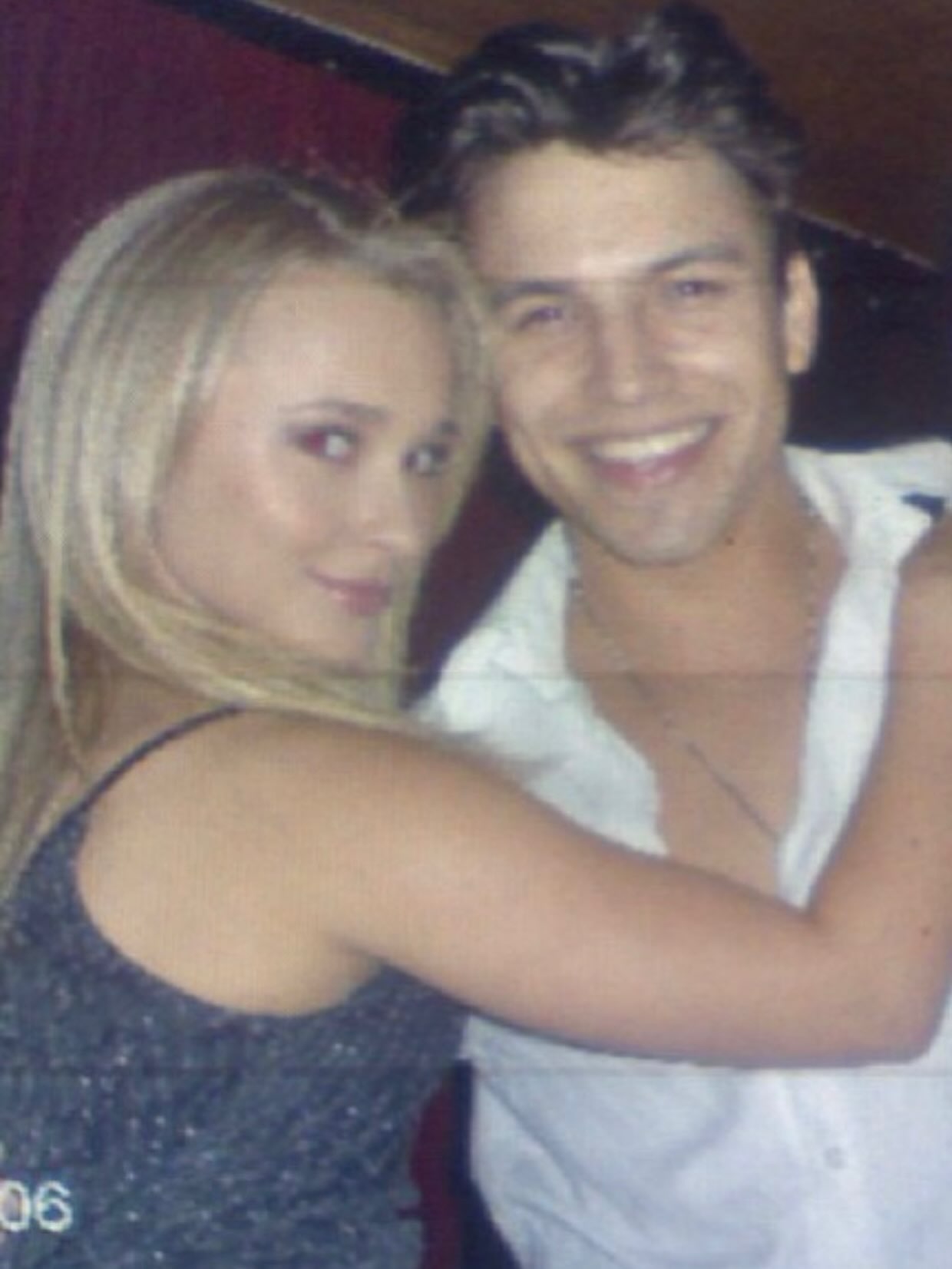 A woman with long blonde hair in a black top and a smiling man in a white shirt with an open collar posing for a photo.