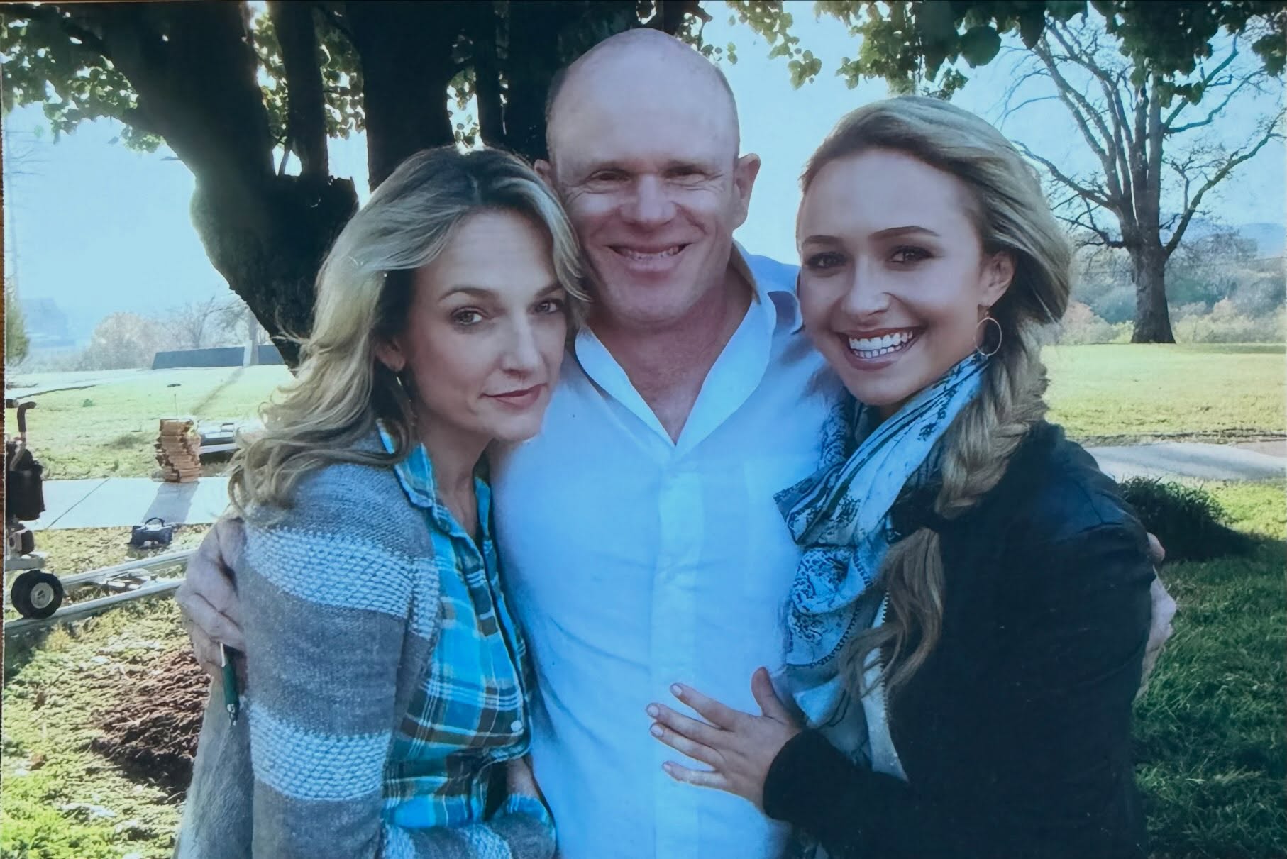 Sylvia Jeffries, a man, and Hayden Panettiere embracing outdoors.