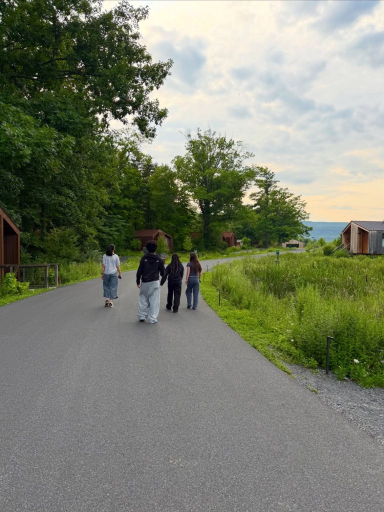 Sandra Bullock's two children and two other people walking on a paved road surrounded by nature.