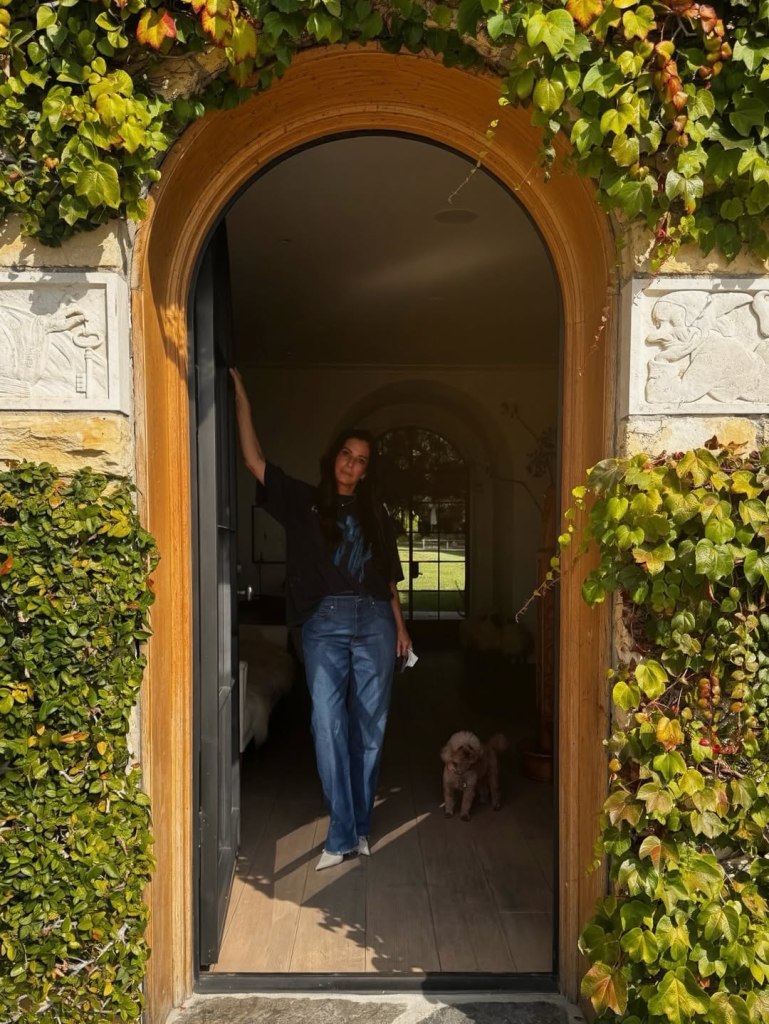 Sandra Bullock standing in a doorway with a small dog.