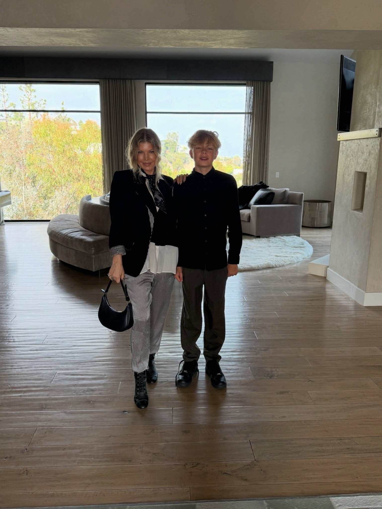 Fergie and son Axl in a modern living room with large windows overlooking trees.