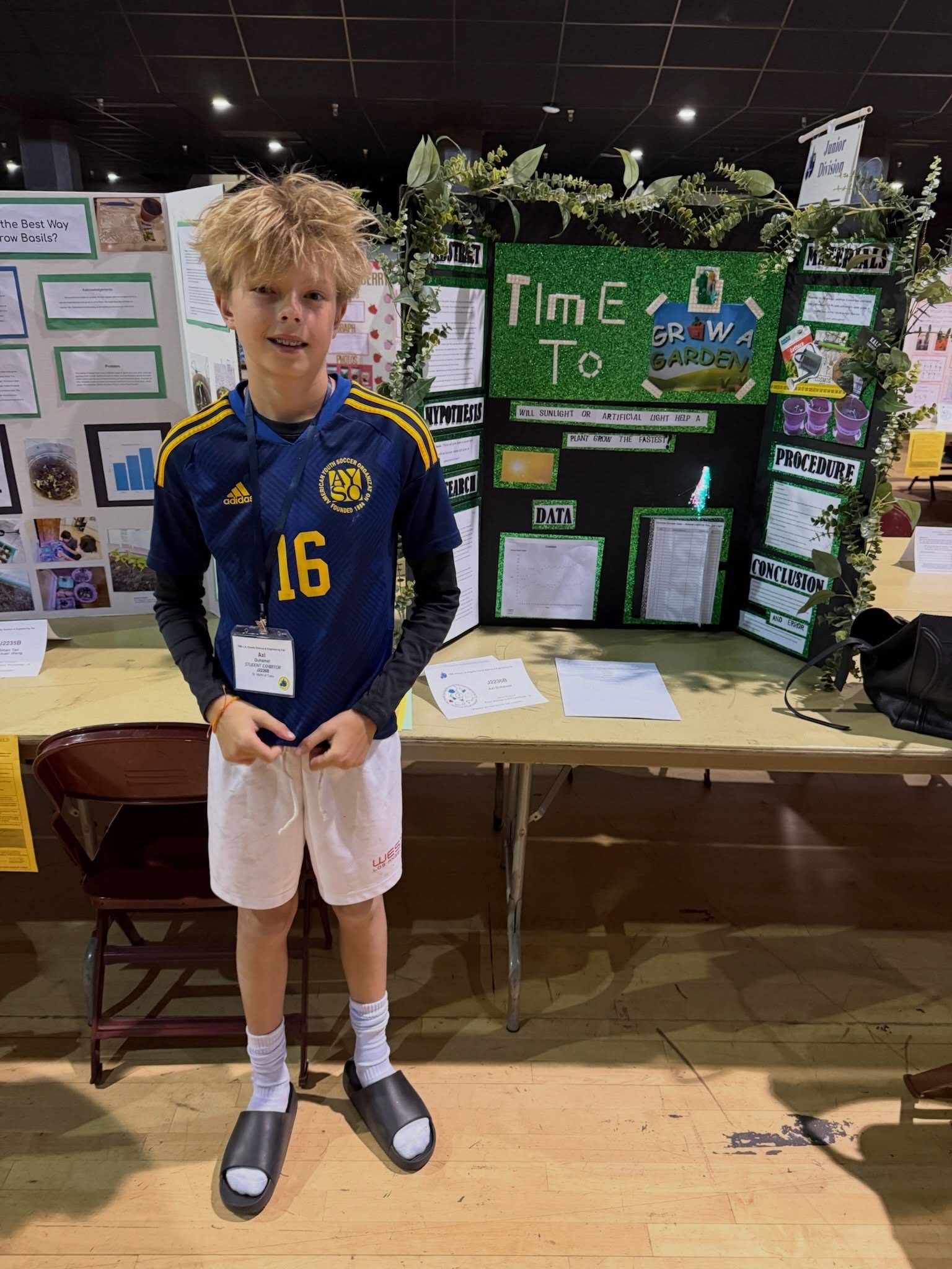 Axl Duhamel standing in front of his science fair project titled 