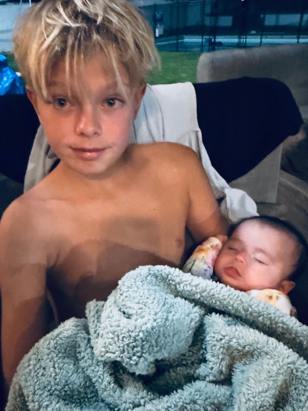Axl Duhamel, the son of Fergie and Josh Duhamel, holding a newborn baby wrapped in a blanket.